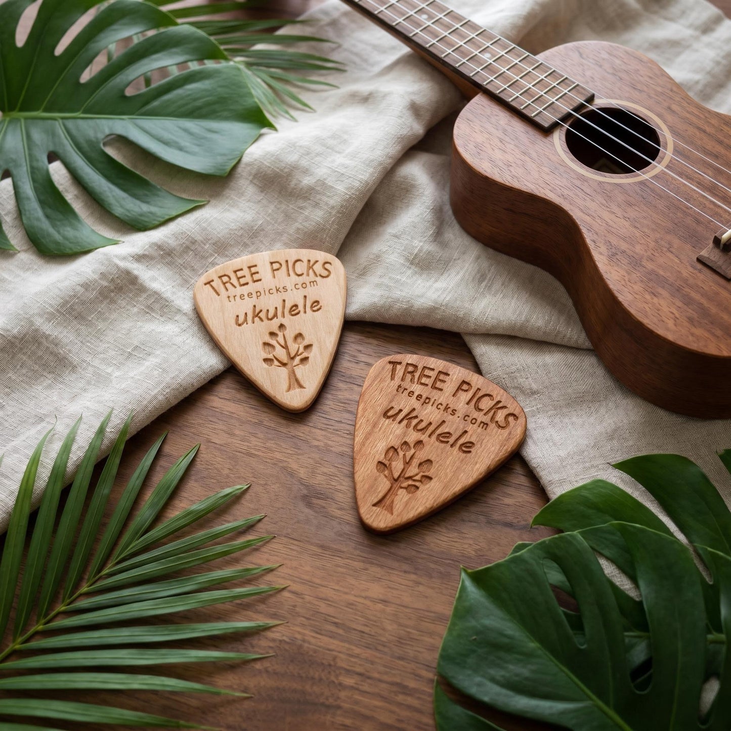 Wooden ukulele picks with 'Tree Picks' branding on a wooden surface with a ukulele and leaves.