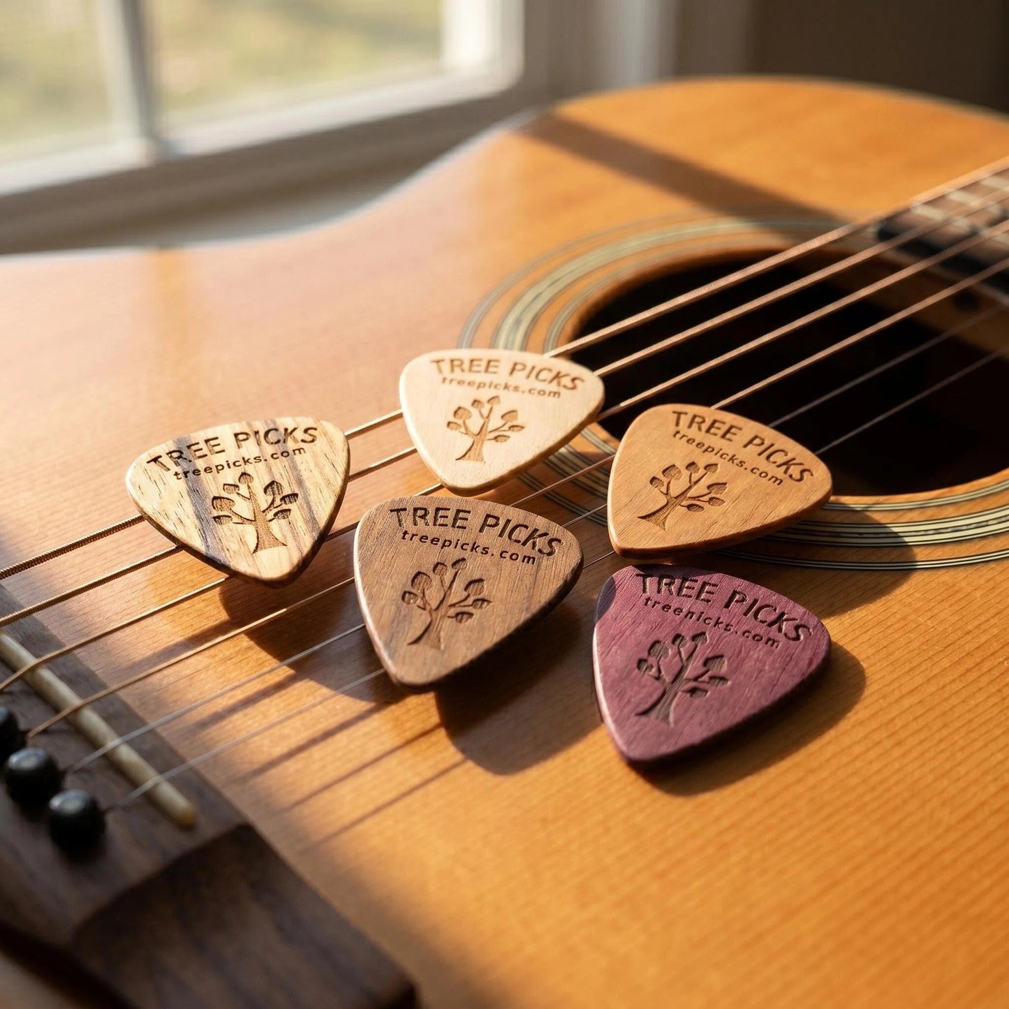 5 Tree Picks Wooden guitar picks on an acoustic guitar