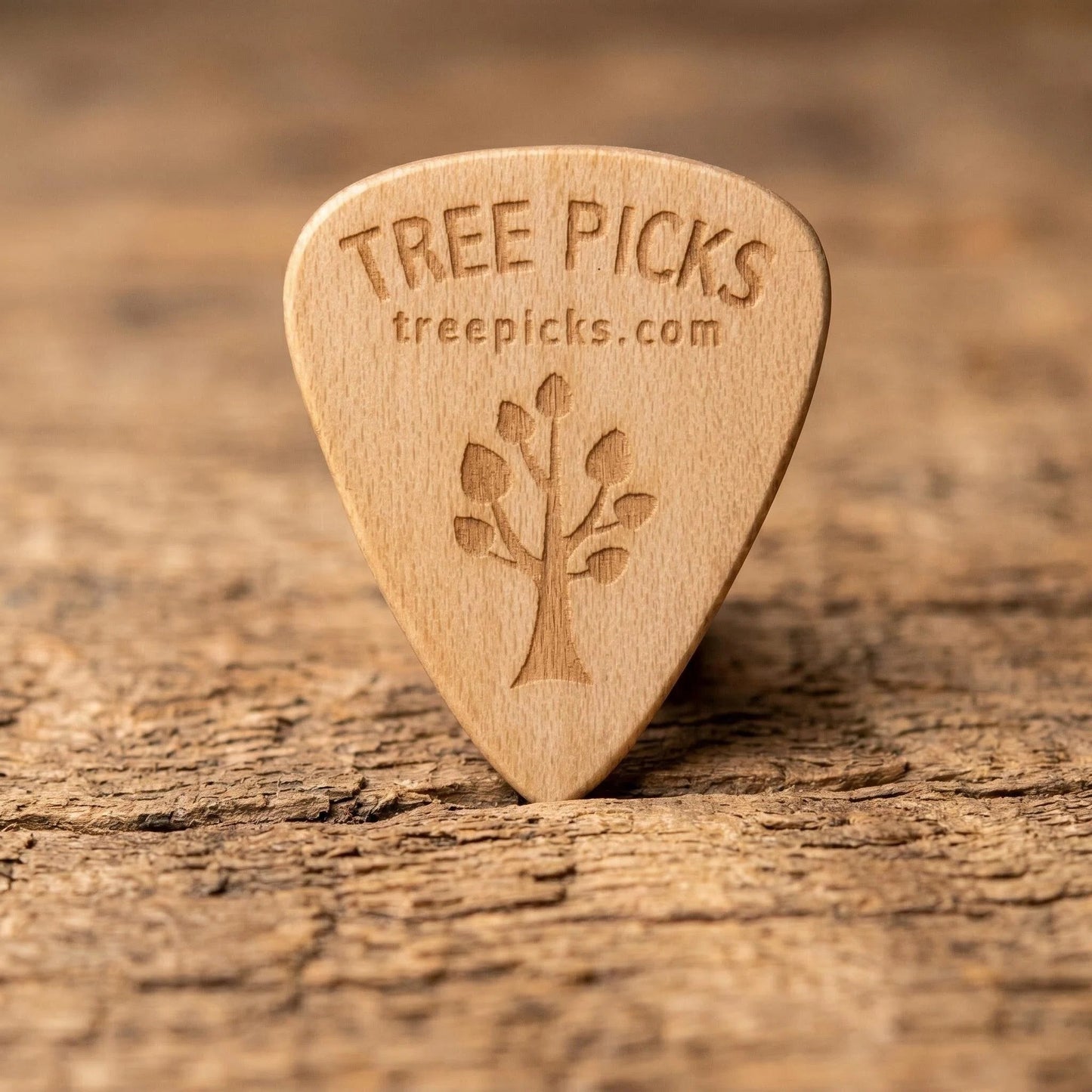 Maple wood guitar pick with 'Tree Picks' branding on a wooden surface
