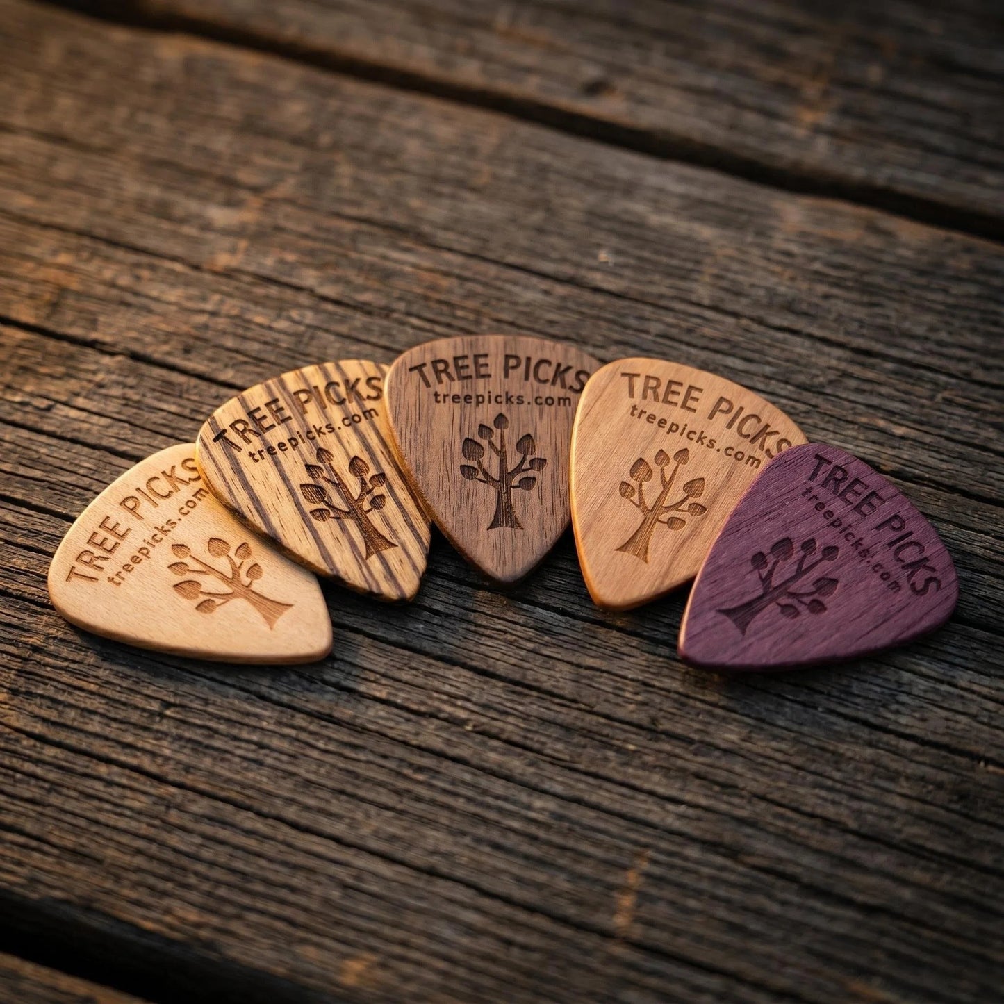 Set of wooden guitar picks with 'Tree Picks' branding on a rustic surface